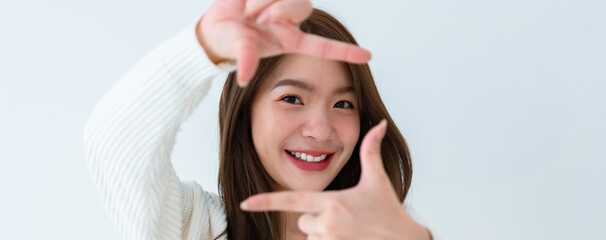Closeup young Asian woman happy and making frame with fingers on white background in house