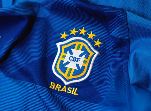 Close-up of the Brazil national football team jersey with embroidered CBF logo and five championship stars on blue fabric.