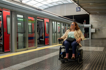 Woman using wheelchair waiting for subway train in accessible station. Concept of inclusion, adapted