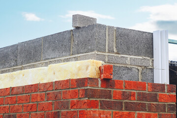 Insulating walls of new build houses by placing rock wool inside wall cavities as part of the...