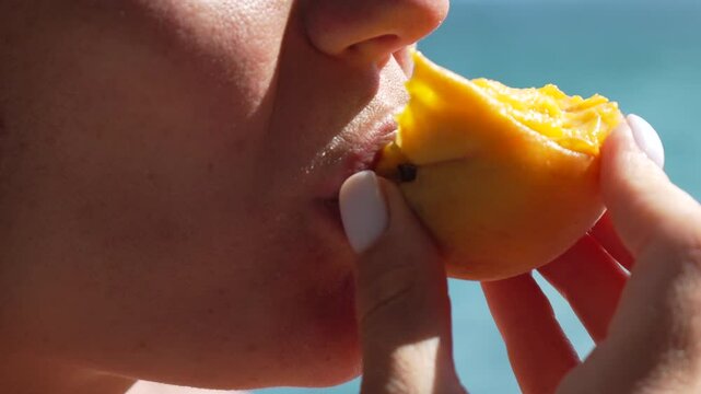 Mango Eating Summer: Woman enjoys ripe mango slice outdoors on a sunny day for taste.