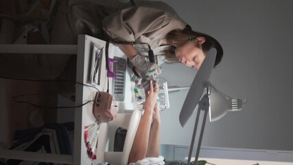 Vertical video of a nail technician performing an e-file manicure in a beauty salon.