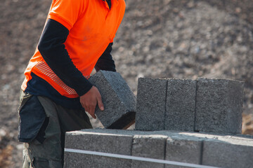 Example of manual handling as bricklayers moving concrete footing blocks by hand on building site
