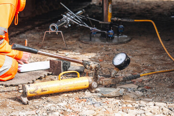 Geotechnical technician using gauges to perform California Bearing Ratio (CBR) test of the ground before works can continue on construction of new road