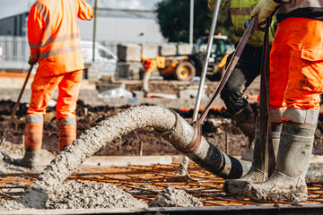 Close-up of Concreters builders using concrete pump to pour wet concrete at building site