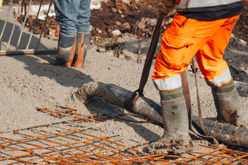 Close-up of Concreters builders using concrete pump to pour wet concrete at building site
