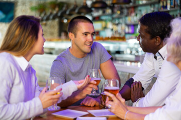 Fototapeta premium Spending time in bar. Four positive friends drinking beer in bar