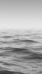 Blurred monochromatic view of water waves under a bright overcast sky creating a textured abstract backdrop with smooth