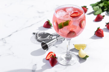 Strawberry gin tonic cocktail on white marble background. Copy space