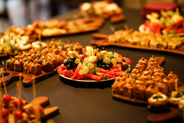 Beautifully arranged catering table with fresh fruit platter, desserts, and canapés, prepared for a festive event or elegant reception.