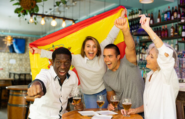 Obraz premium Happy diverse group celebrating Spain at a bar with beer