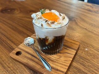 Black coffee with whipped egg white foam, finished with an egg yolk on top