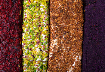Turkish delight rolls with dried cranberries, pistachios, roasted hazelnuts and freeze dried berry powder. Texture close-up, top view