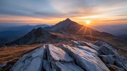 A breathtaking view of a jagged mountain range at sunset reveals spectacular colors as the sun sets, illuminating the rocks and reflecting beautifully on the calm waters.