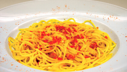 Spaghetti with bottarga and chili pepper lying in a white plate