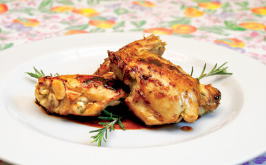 Delicious roasted chicken legs seasoned with rosemary lying on white plate