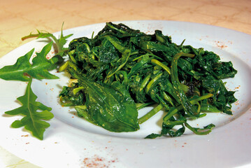 Sauteed chicory and rocket salad on white plate