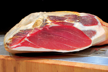 Large piece of prosciutto resting on wooden cutting board
