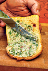 Chef spreading tuna and parsley sauce on toasted bread slice