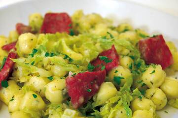 Potato gnocchi with savoy cabbage and cured pork meat seasoned with parsley