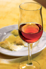 Glass of amber wine with cheese on a plate on yellow tablecloth