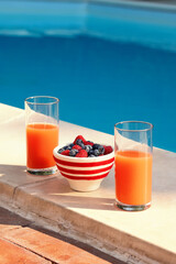 Healthy summer breakfast with fresh berries and juice by the swimming pool
