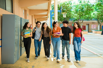 Obraz premium Full length view of a group of gigh school students walking and talking in school hallway