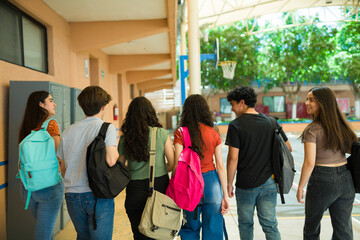 Obraz premium Rear view of a group of high school students walking down school hallway after class