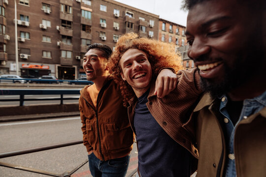 Three young men laughing and walking in the city