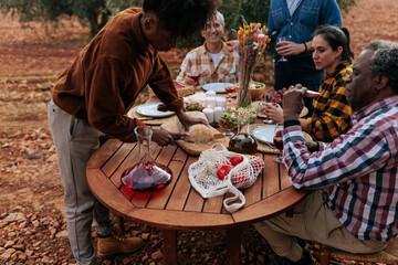 Family and friends gathering enjoying outdoor meal in olive grove