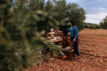 Farmers toasting with red wine in olive grove after harvesting olives