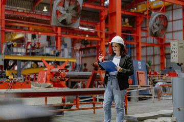 Woman engineer manager working at steel production factory. Female inspector wears safety hard hat...