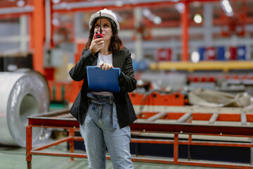 Woman engineer manager standing at steel production factory. Female inspector wears safety hard hat...