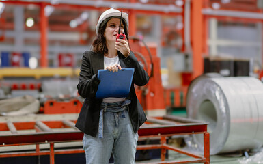 Woman engineer manager standing at steel production factory. Female inspector wears safety hard hat...