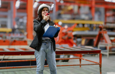 Woman engineer manager standing at steel production factory. Female inspector wears safety hard hat...