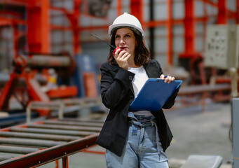 Woman engineer manager standing at steel production factory. Female inspector wears safety hard hat...