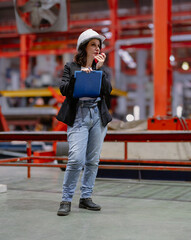Woman engineer manager standing at steel production factory. Female inspector wears safety hard hat...