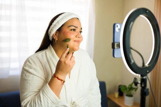 Plus size influencer making beauty tutorial video using jade roller