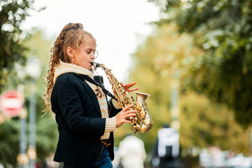 Young girl playing saxophone during an outdoor performance.