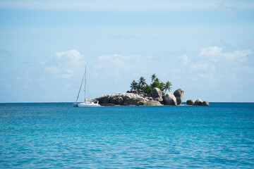 Fototapeta premium Catamaran passing near the l'ilot rocky island, turquoise water, Mahe Seychelles