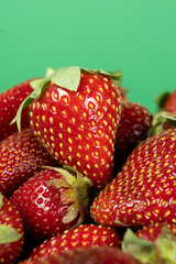 Pile of fresh ripe strawberries on a green background