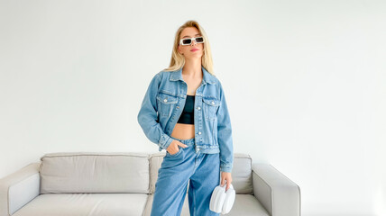 A fashion photography shot of a young woman in a casual denim outfit against a plain white background