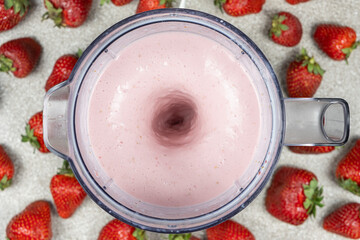 The process of making a strawberry milkshake, whisking all the ingredients in a blender.