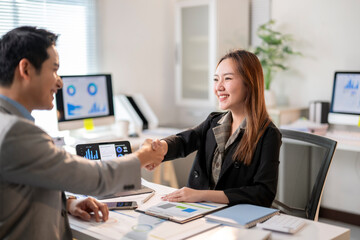 A man shakes hands with a woman in a business setting