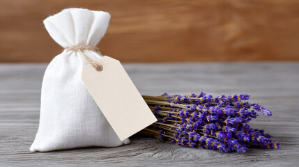 Calm and natural scene with dried lavender flower bundle and white cloth sachet bag on wooden table. For relaxing aromatherapy, wellness, or herbal gift with blank tag