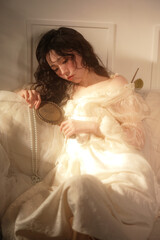 Female model with a mirror and pearls in soft light.