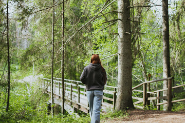 Fototapeta premium Red hair woman walking in nature in the forest for health. Travel to another country for hiking