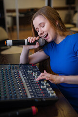 Young woman mixing live sound. Girl recording a song in the studio. 