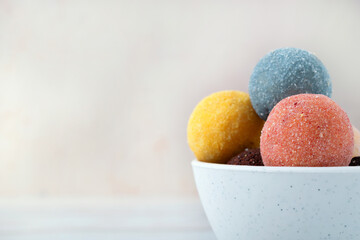 Candies made from dried fruits and nuts with berry, lemon and lavender flavors in a white bowl on a light background. Healthy handmade dessert. Copy space