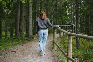 Fototapeta premium Red hair woman walking in nature in the forest for health. Travel to another country for hiking
